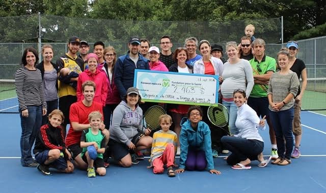 Les participants du tournoi de tennis posent fièrement avec le grand chèque annonçant le montant amassé.