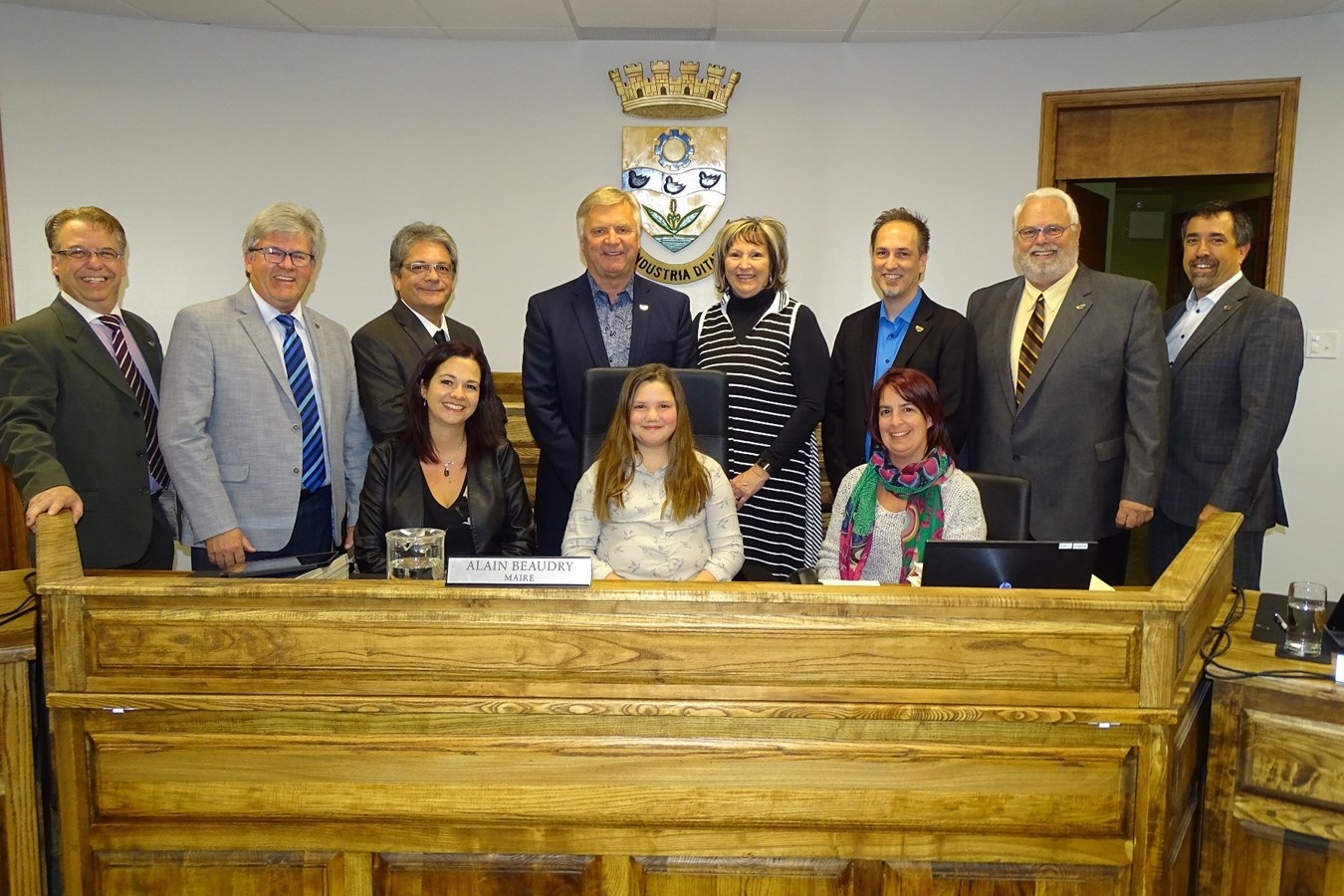 Amélie-Rose pose fièrement installée dans la chaise du maire, entourée de sa mère, de son enseignante et du conseil municipale de la Ville de Joliette