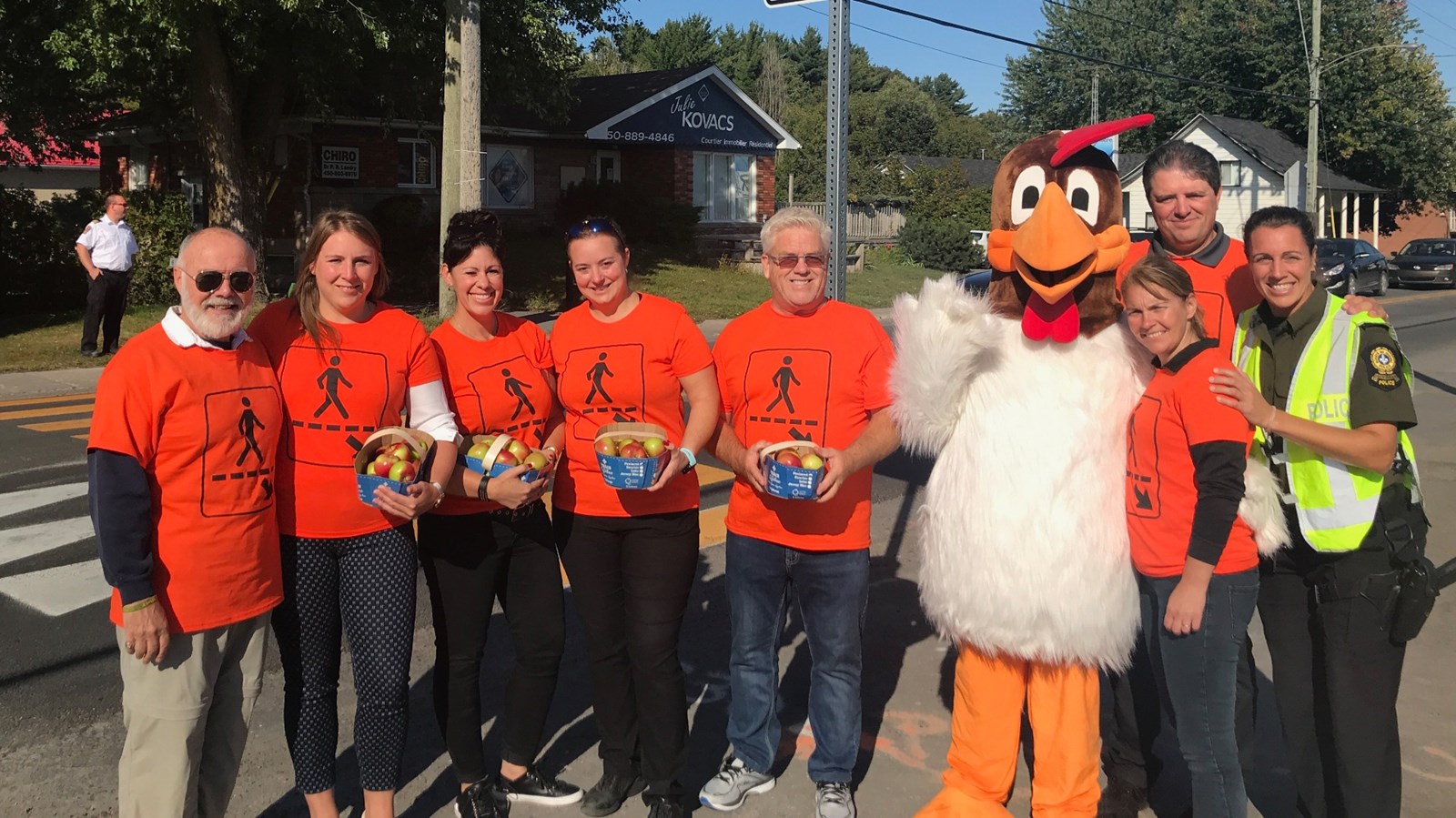 Les partenaires du projet: Denis Renaud, conseiller; Audrey Boisjoly, mairesse; Marie-Christine Hivon, directrice de l'école des Moulins; Josyane Rainville, IGA Rainville; Sylvain Trudel, conseiller; Félico, mascotte; Josée Frenette, technicienne d'intervention en loisirs à l'Érablière; Daniel Frappier, directeur de l'Érablière et Audrey Bastien, coordonnatrice locale en police communautaire à la Sûreté du Québec. En arrière-plan, Dominic Bibeau, directeur adjoint Sécurité incendie.