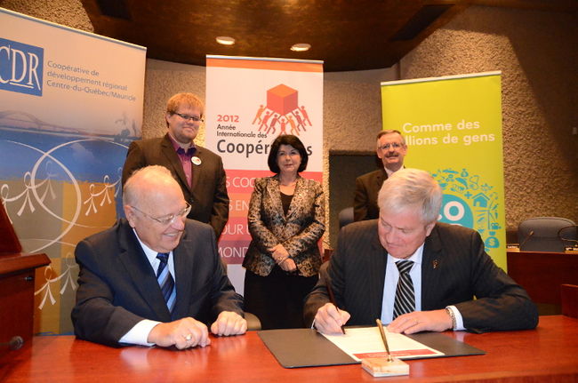 Fernand Lajoie, maire suppléant de Trois-Rivières et Gérard Bruneau, président de la Conférence régionale des élus de la Mauricie, signent la Déclaration à l’occasion de l’Année internationale des coopératives 2012. En arrière-plan : Jean-Emmanuel Bouchard, représentant du Conseil québécois de la coopération et de la mutualité, Francine Ruest-Jutras, présidente de la CRÉ du Centre-du-Québec, et Michel Gauthier, président de la coopérative de développement régional Centre-du-Québec/Mauricie.