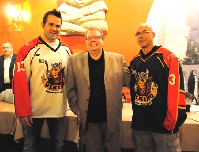 Le défenseur Thomas Bellemare et l’entraîneur Alain Côté portent les nouvelles couleurs du Viking. Ils entourent le président et directeur général de l’équipe Léo-Guy Morissette.