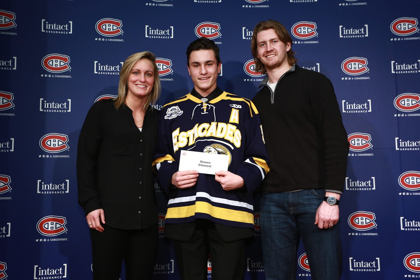 Shawn Élément, au centre, reçoit sa bourse des mains de Marie-Philip Poulin, ancienne boursière et joueuse des Canadiennes de Montréal ainsi que Jeff Petry, défenseur du Canadien de Montréal.