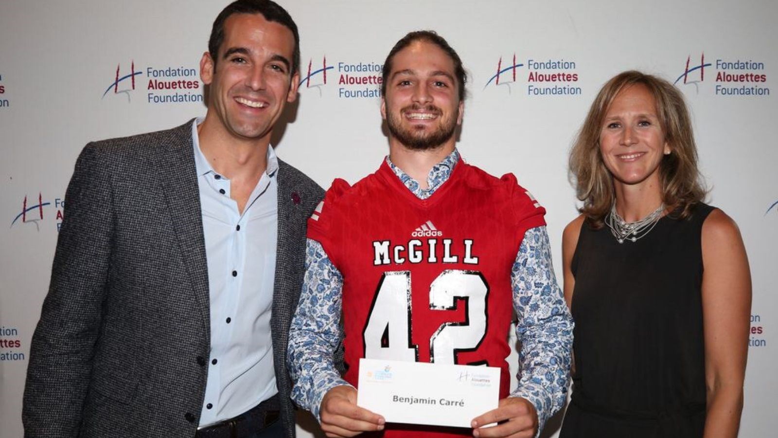 Benjamin Carré a reçu une bourse de 1 000 $ des mains de Patrick Boivin des Alouettes de Montréal et Marie-Eve Bergeron de Bell Média.