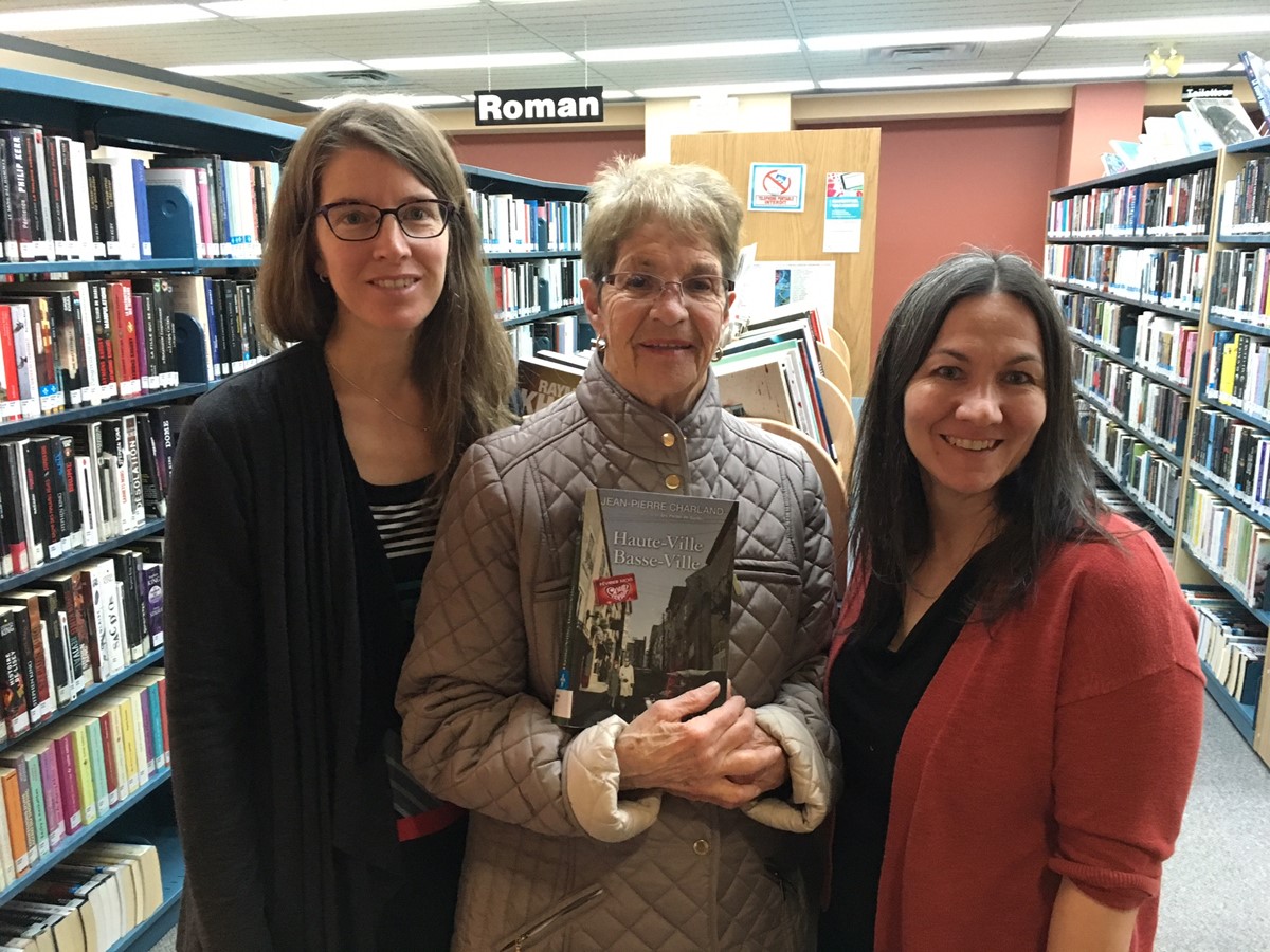 Accompagnée des commis à la bibliothèque Caroline Pleau et Maryse Garant, la gagnante Yolande Letendre pose avec son coup de cœur 2018.