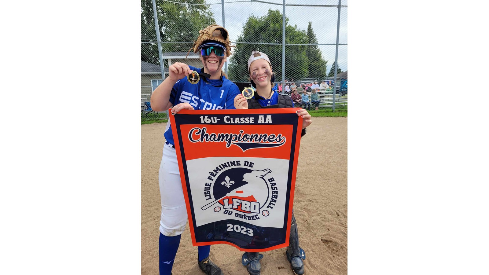 Marilou Boilard et Sophie Duval posent en compagnie de la bannière de Championnes de la catégorie 16UAA.