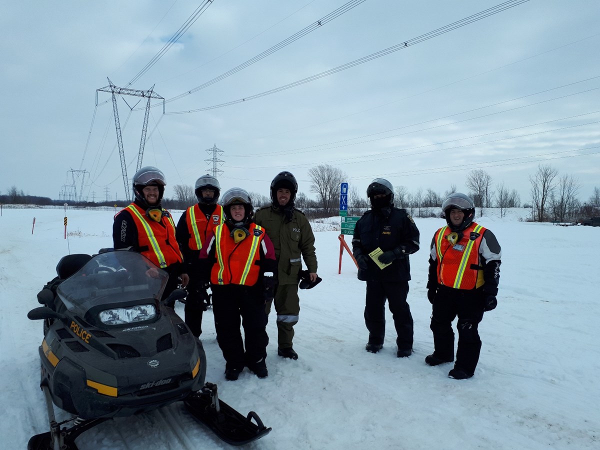 Deux policiers de la Sûreté du Québec accompagnés de patrouilleurs du Club Harfangs des Neiges.