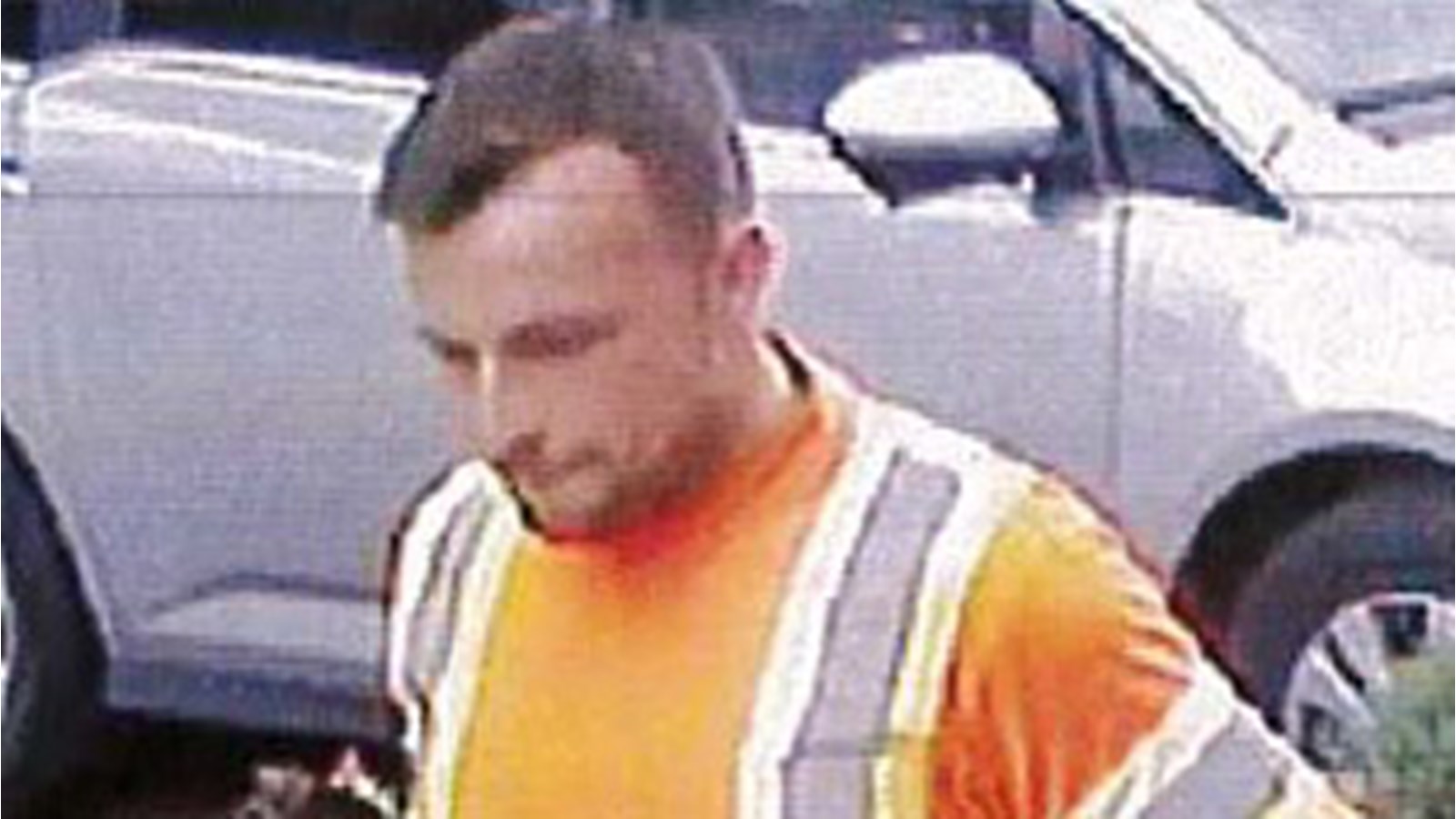 Environ 25 ans, il porte une barbe taillée et a les cheveux bruns. Il est vêtu d’une veste orange de travailleur, d’un pantalon bleu marine et de bottes de travail brunes.