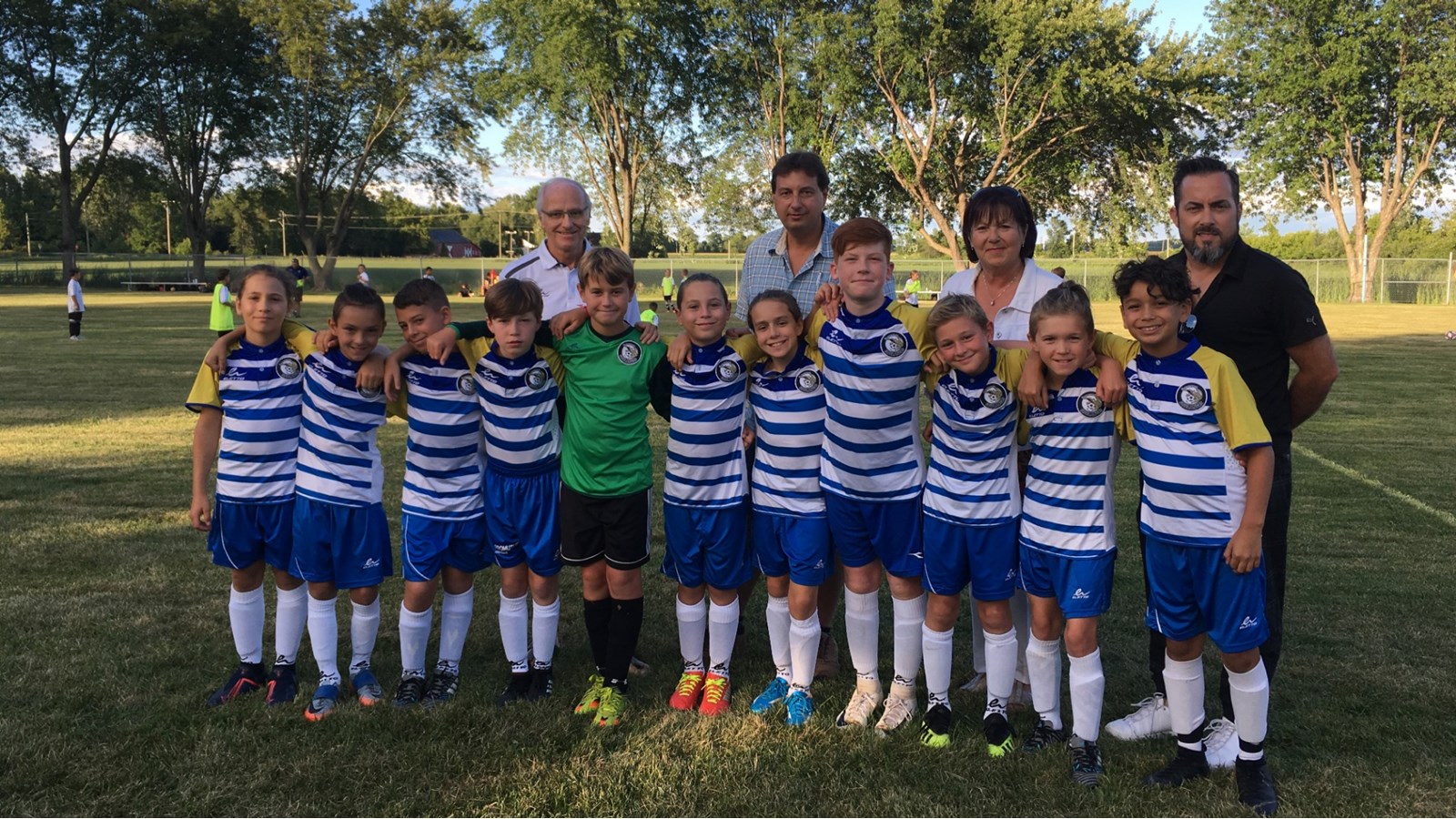 Le président de la Ligue de soccer Soulanges, Robert Lapointe, le conseiller municipal de Les Coteaux, Sylvain Brazeau, la mairesse Denise Godin-Dostie et le conseiller municipal Dominic Leduc prennent la pose avec des joueurs de la région.