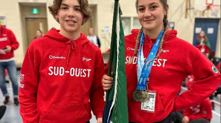 Ève-Mahée Christophe de Notre-Dame-de-l'Île-Perrot, triple médaillée d’or en haltérophilie, a remis le drapeau du Sud-Ouest à Noah de l' équipe de hockey en guise de bonne chance pour le second bloc des compétitions