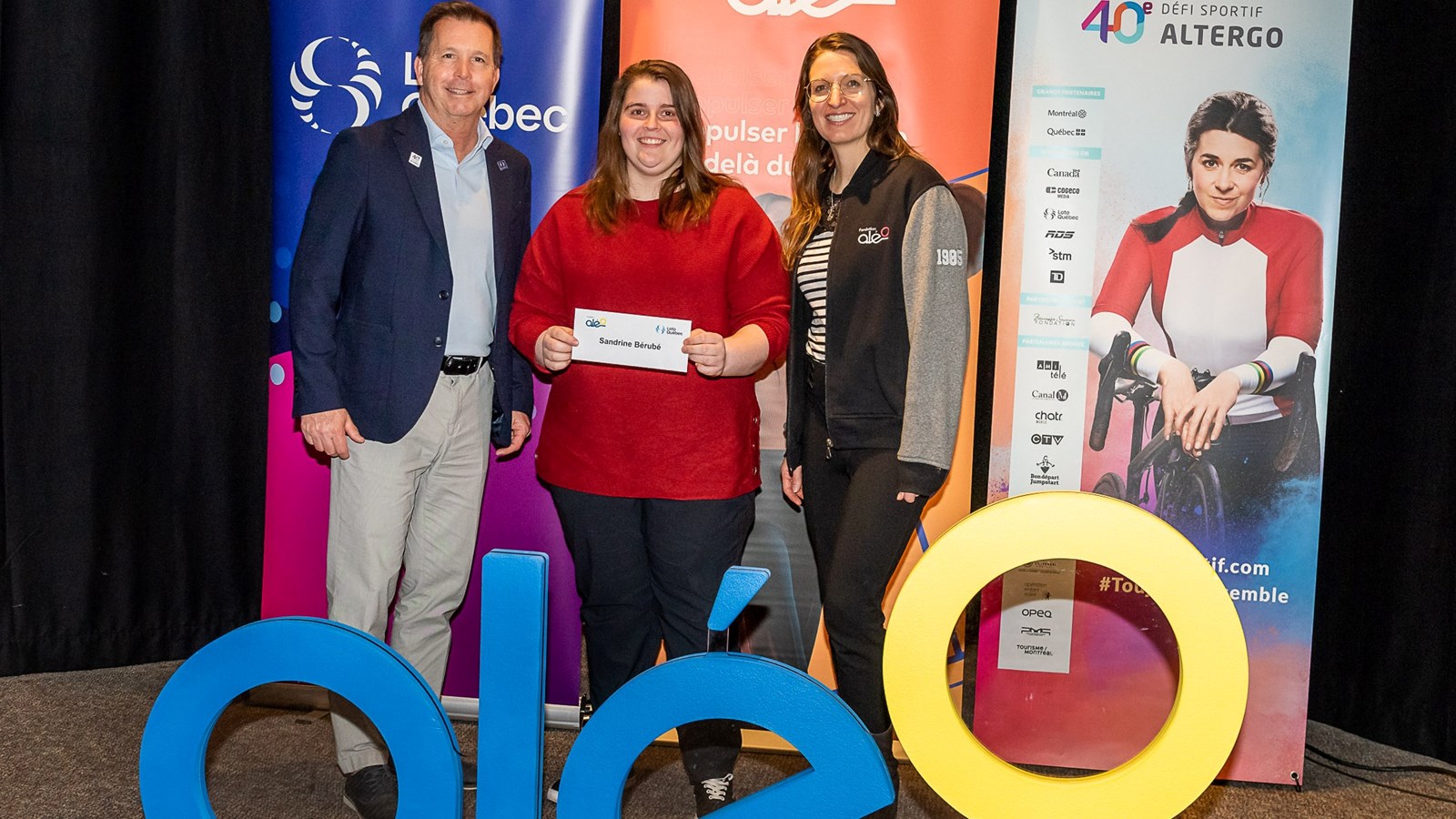 Sur sa photo de remise, Sandrine est en compagnie d’Eric Meunier, directeur de l’engagement sociétal chez Loto-Québec, et de Sophie Brassard, PhD, C.O., responsable des services aux athlètes à la Fondation Aléo