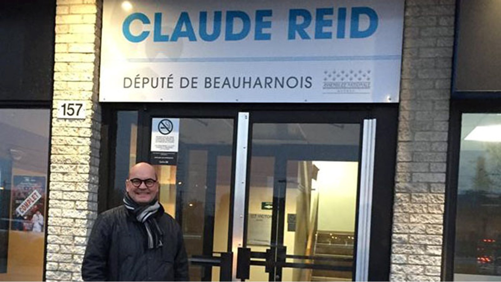 Le député Claude Reid pose devant son local électoral situé à Salaberry-de-Valleyfield.