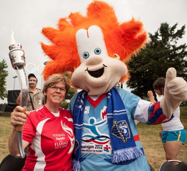 Jocelyne Bourassa, ambassadrice de la finale des Jeux du Québec, et la mascotte Flammèche sont en route pour Shawinigan avec le flambeau des Jeux.