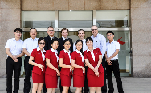 Devant les bureaux d’usine de la compagnie à Dongguan, en Chine. On y reconnaît, dans la rangée du haut, à partir de la gauche : M. Gerry Préfontaine (3e), Me Sébastien Gariépy, avocat (4e) et M. Martin Bénard (5e) avec les employés de bureaux de la compagnie.