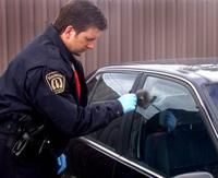 Sylvain Gauthier dépose la poudre dactyloscopique sur la vitre de voiture afin de détecter les empreintes digitales.