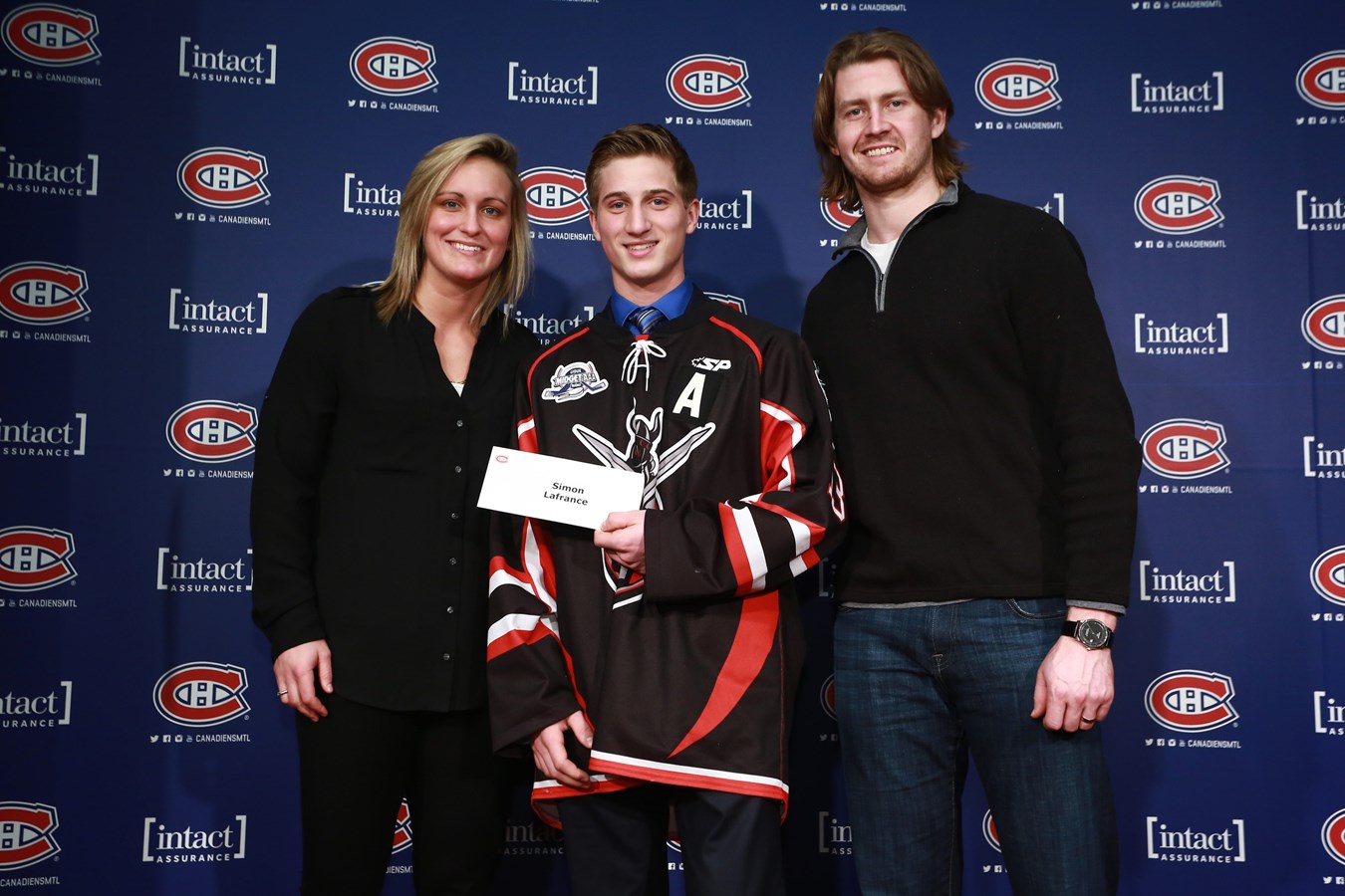 Simon Lafrance, au centre, reçoit sa bourse des mains de Marie-Philip Poulin, ancienne boursière et joueuse des Canadiennes de Montréal ainsi que Jeff Petry, défenseur du Canadien de Montréal.