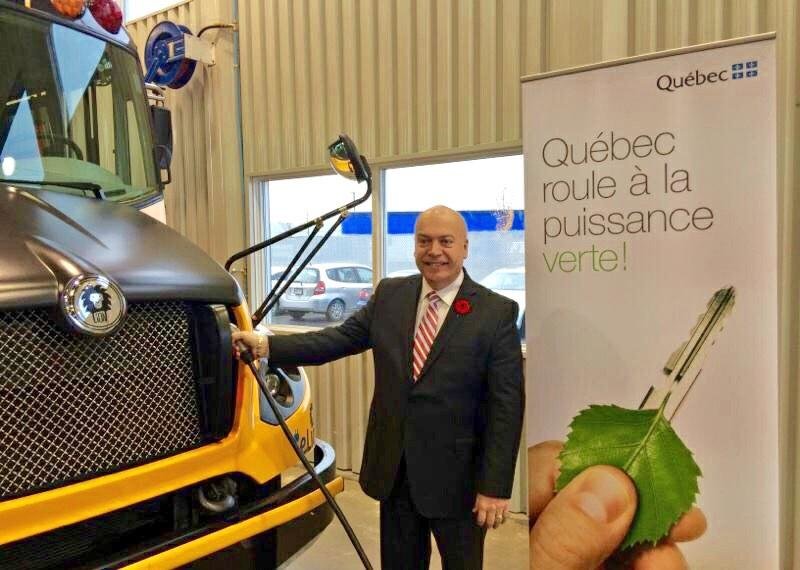 Le ministre des Transports, Robert Poëti, procède à la recharge de l'autobus.