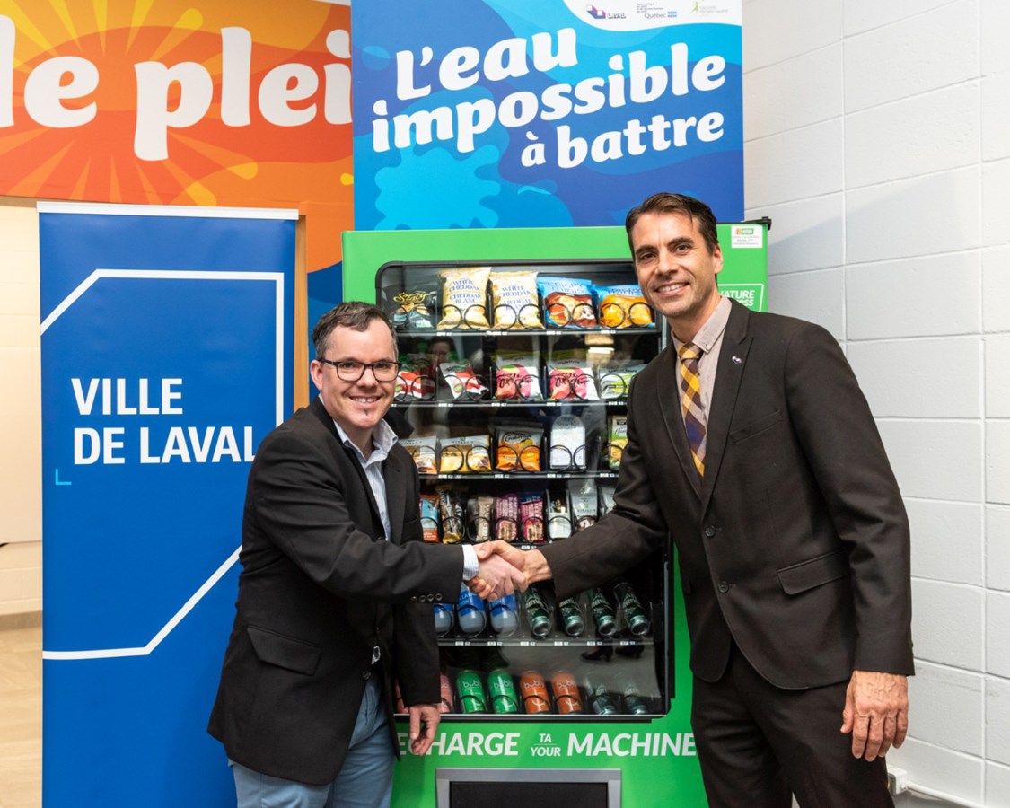 Le Dr Jean-Pierre Trépanier, directeur de santé publique du CISSS de Laval et Nicholas Borne, conseiller municipal de Laval-les-Îles, responsable du développement social devant une machine distributrice santé, à l’aréna Hartland-Monahan.
