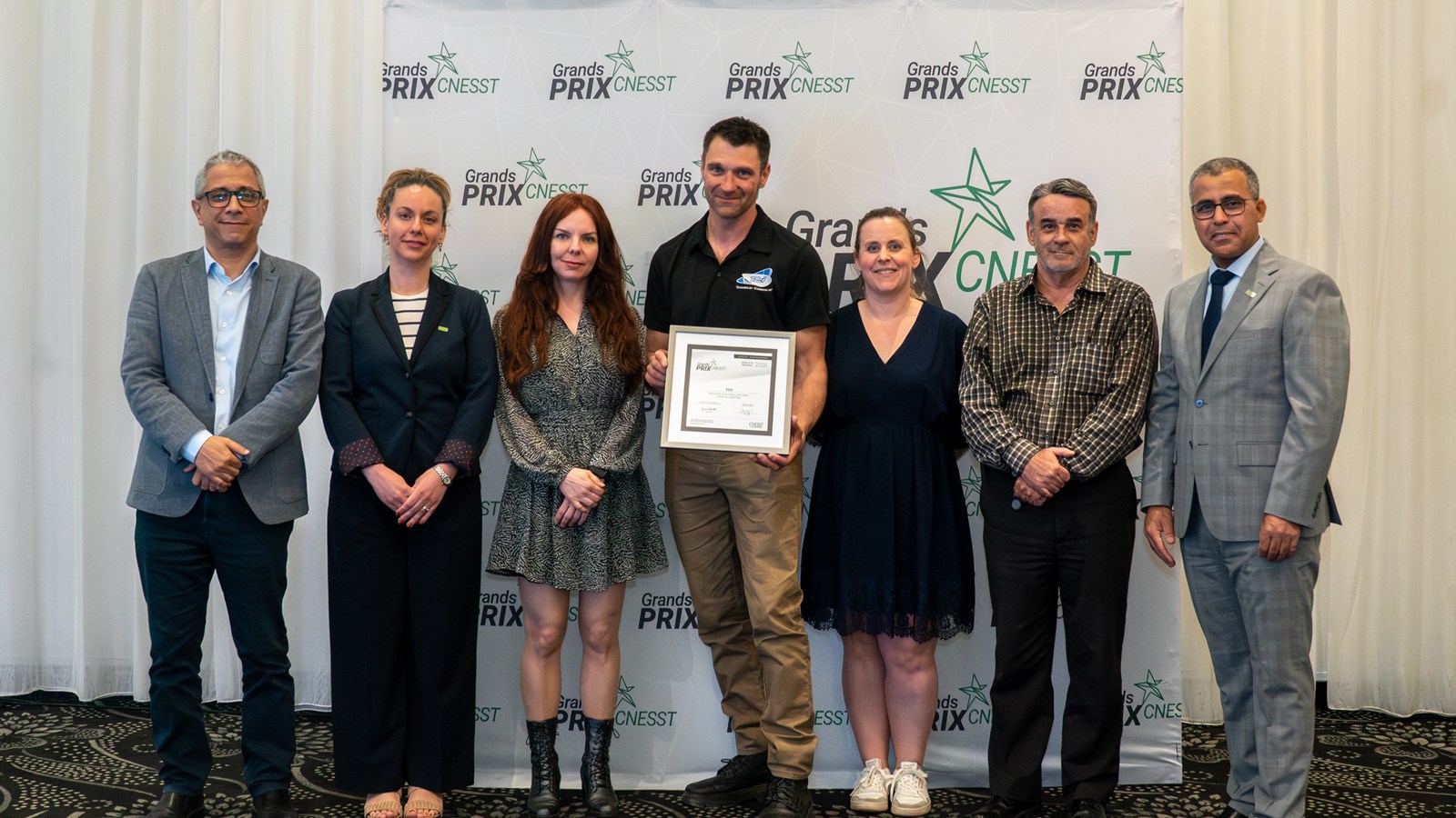 Les représentants de l'entreprise TCI+ prennent la pose avec une plaque honorifique remise lors des Grands Prix de la CNESST