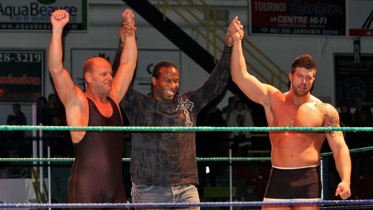 Les champions de la soirée, Jacques Rougeau et Cédric Rougeau, entourent Georges Laracque.