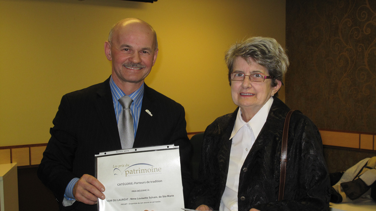 Louisette Sylvain reçoit le prix Porteur de tradition des mains du préfet Lehoux.