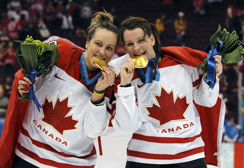 Marie-Phililp et une coéquipière, mordant dans leur médaille d'or acquise à Vancouver