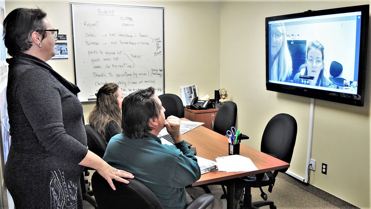 Guylaine Jacques (à gauche), intervenante aux opérations du volet anglophone de Tandem International, Team Air, supervise deux participants qui s'apprêtent à effectuer un appel Skype avec une entreprise d'entraînement de Lévis.