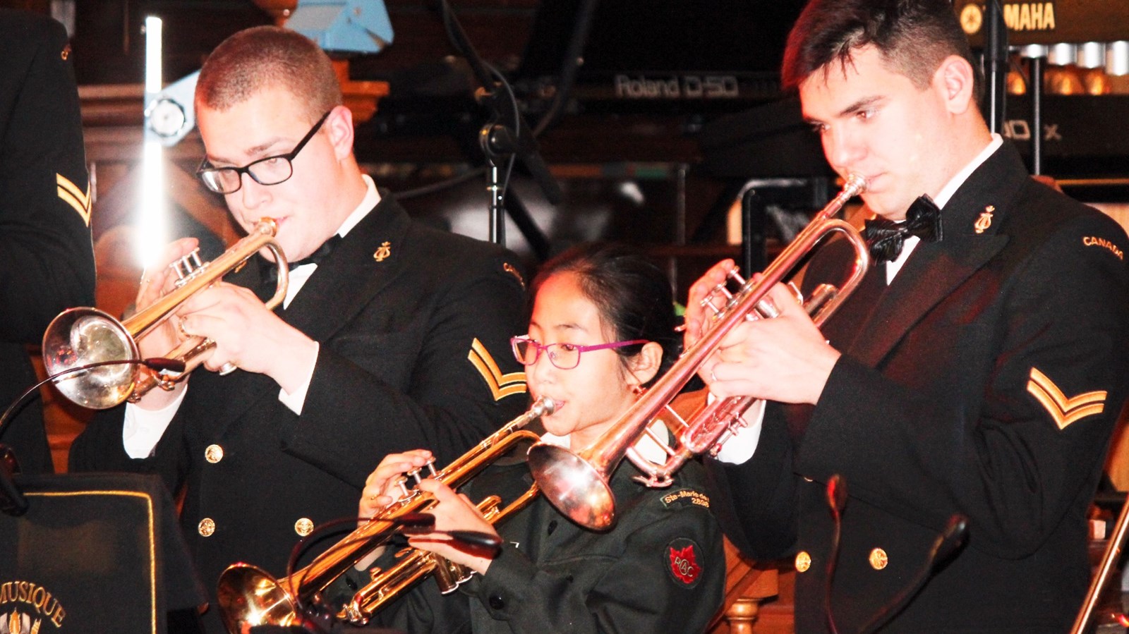 La cadette Marie-Lee Gingras du corps de cadets 2898 de Sainte-Marie-de-Beauce aux côtés de deux musiciens du NCSM Montcalm lors du concert conjoint le 3 décembre dernier à St-Prosper.