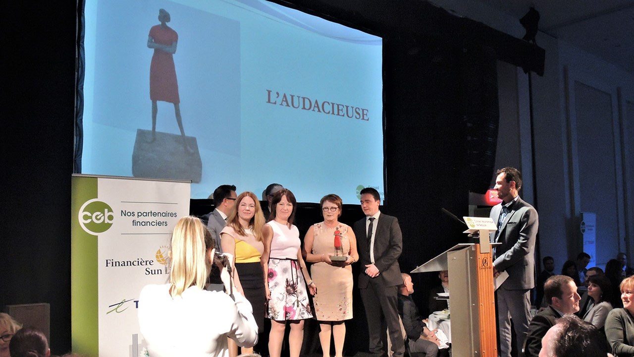Claire Boutin, récipiendaire du Prix Jean-Denis Poulin, entourée de ses enfants, avec la sculpture réalisée par l'artiste beauceron Paul Duval intitulée « L’audacieuse ».