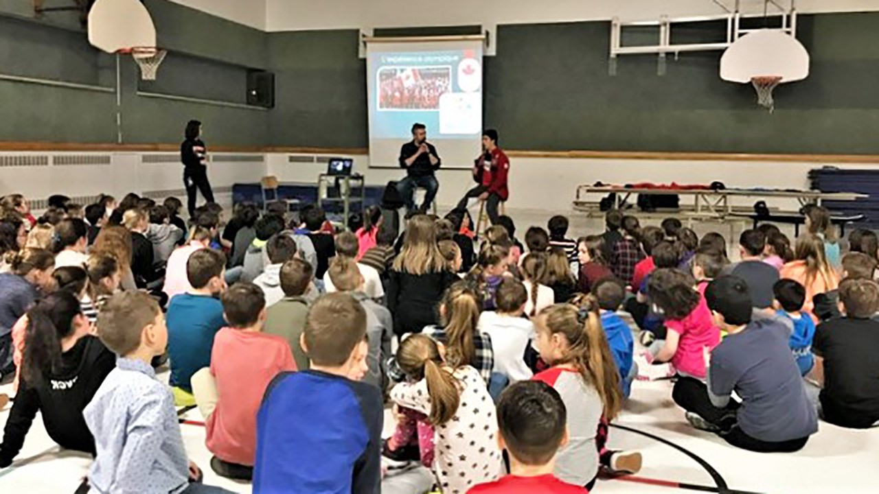 Julien Fecteau, enseignant, et Éliot Grondin, athlète en snowboard cross, devant les élèves de l'école Mgr-Feuiltault de Sainte-Marie.