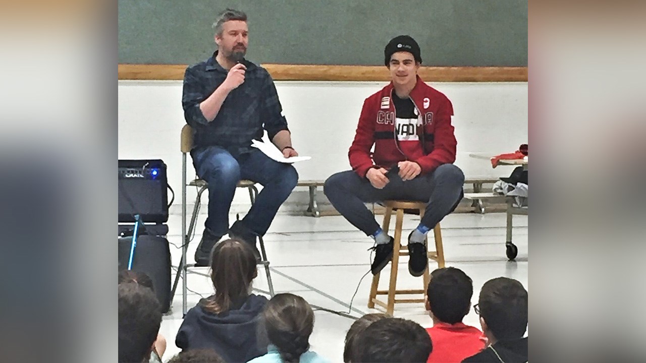 Julien Fecteau, enseignant, et Éliot Grondin, athlète en snowboard cross, devant les élèves de l'école Mgr-Feuiltault de Sainte-Marie.