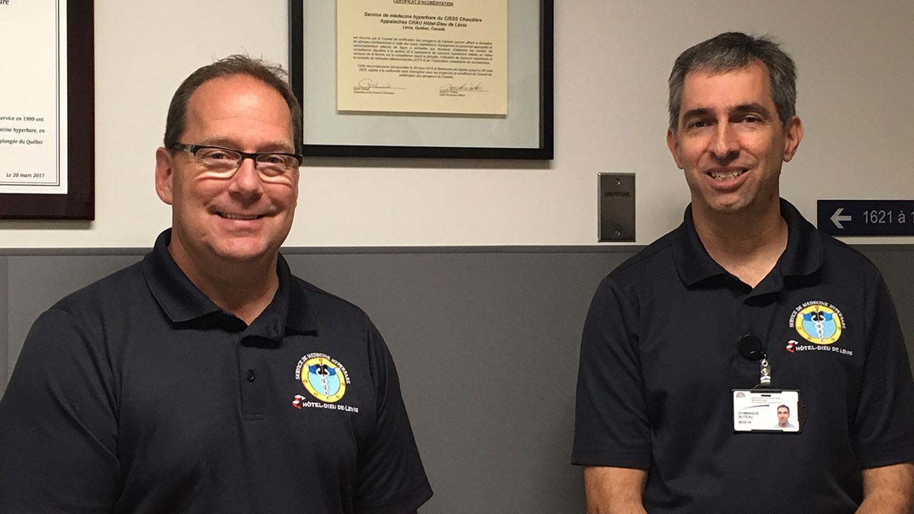 M. Jocelyn Boisvert, responsable de la sécurité hyperbare et Dr Dominique Buteau, directeur médical du Service de médecine hyperbare de l'Hôtel-Dieu de Lévis posent près du certificat confirmant l'accréditation.