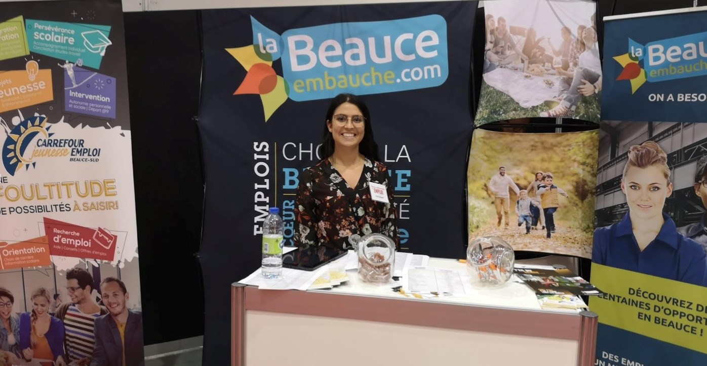 Léa Duquet, nouvelle agente de liaison et de promotion à la Beauce Embauche, devant le kiosque de l’organisme lors du passage à Montréal.