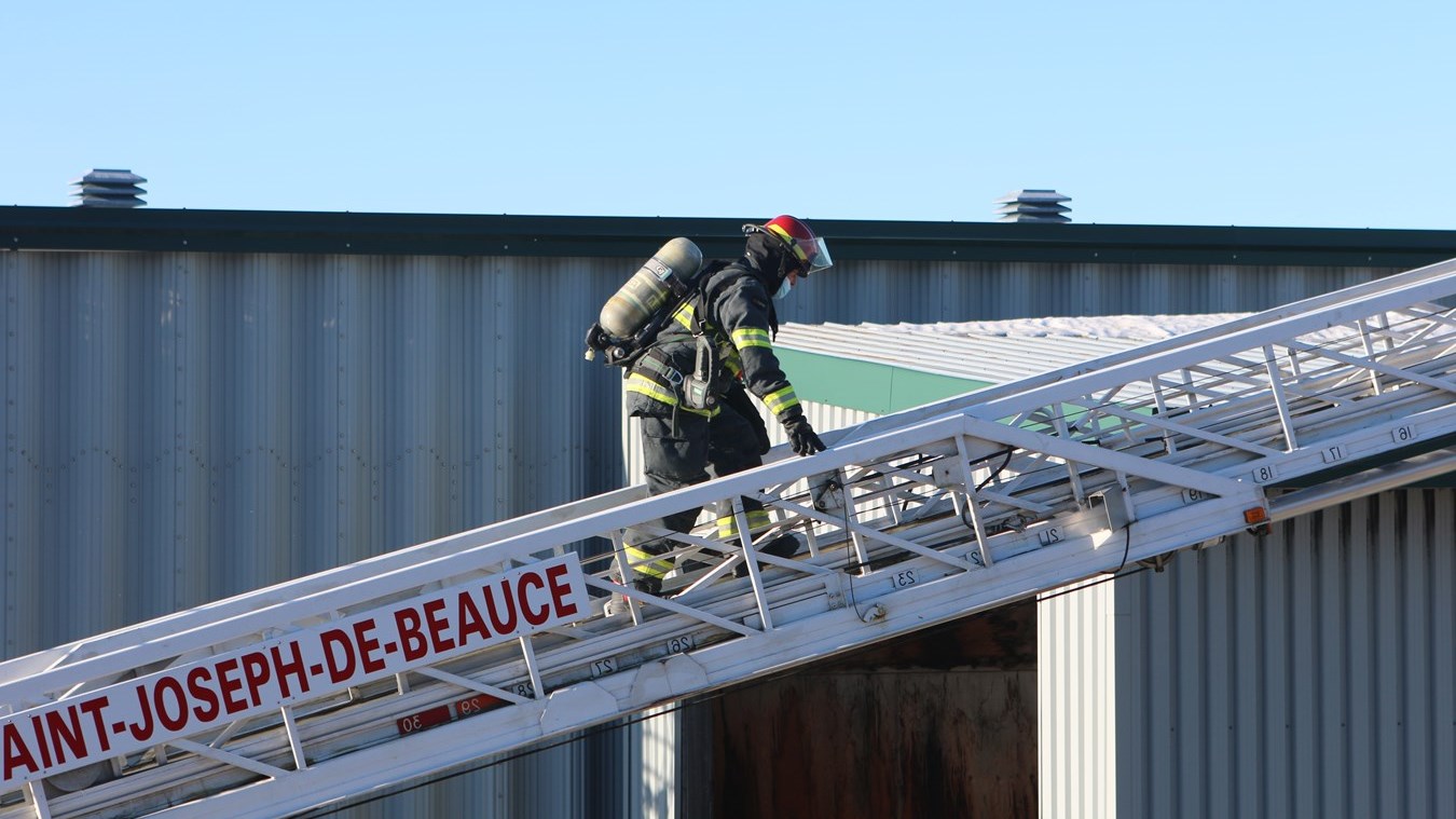Un lieutenant du service incendie de Beauceville montant le camion-échelle du SSI de Saint-Joseph sur une alarme Incendie.