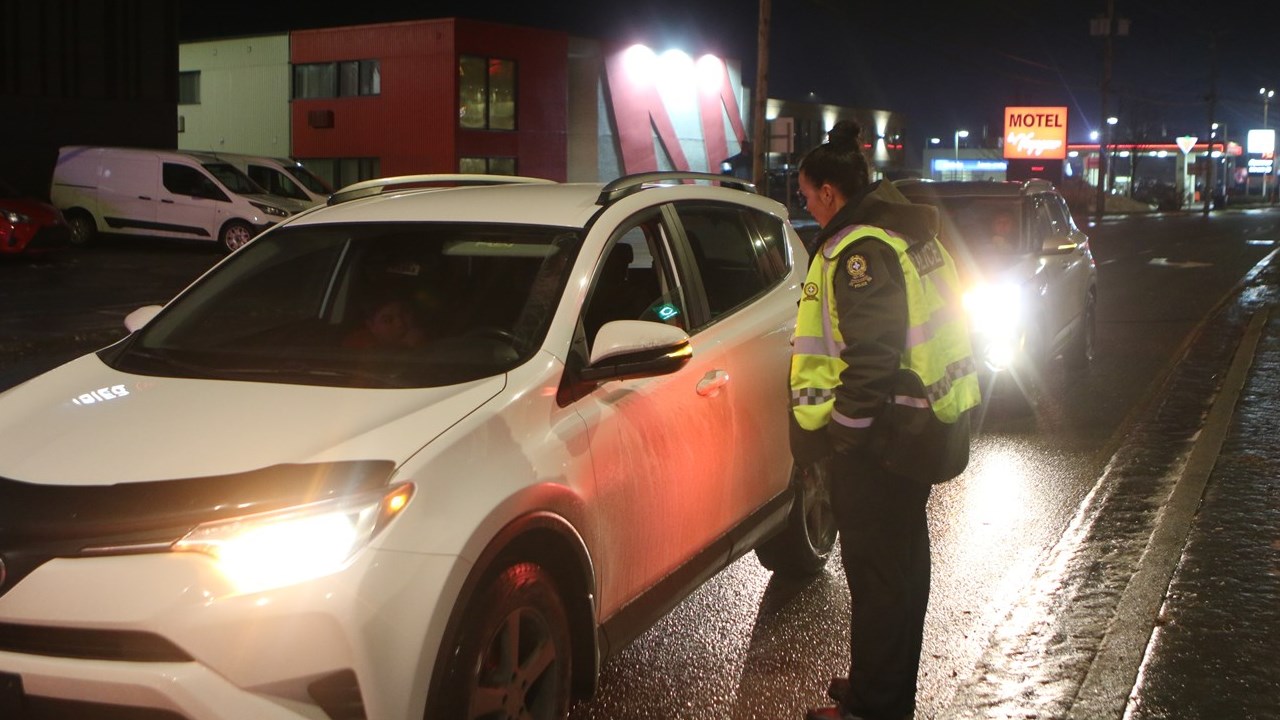 Une agente de la Sûreté du Québec faisant les vérifications d'usages sur un barrage pour l'alcool aux volants.