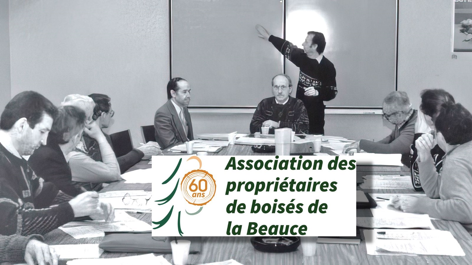 Une réunion du conseil d'administration durant la présidence de Jean-Luc Bilodeau alors que Marcel Giguère agissait comme secrétaire général. En mortaise, le logo qui sera utilisé pour marquer les célébrations tout au long de la prochaine année.