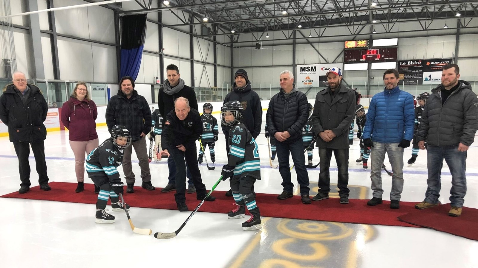 Les jeunes hockeyeurs, Alice Routhier et Félix Auclair, dans leur nouvel uniforme en compagnie des commanditaires du hockey plaisir Adstock.