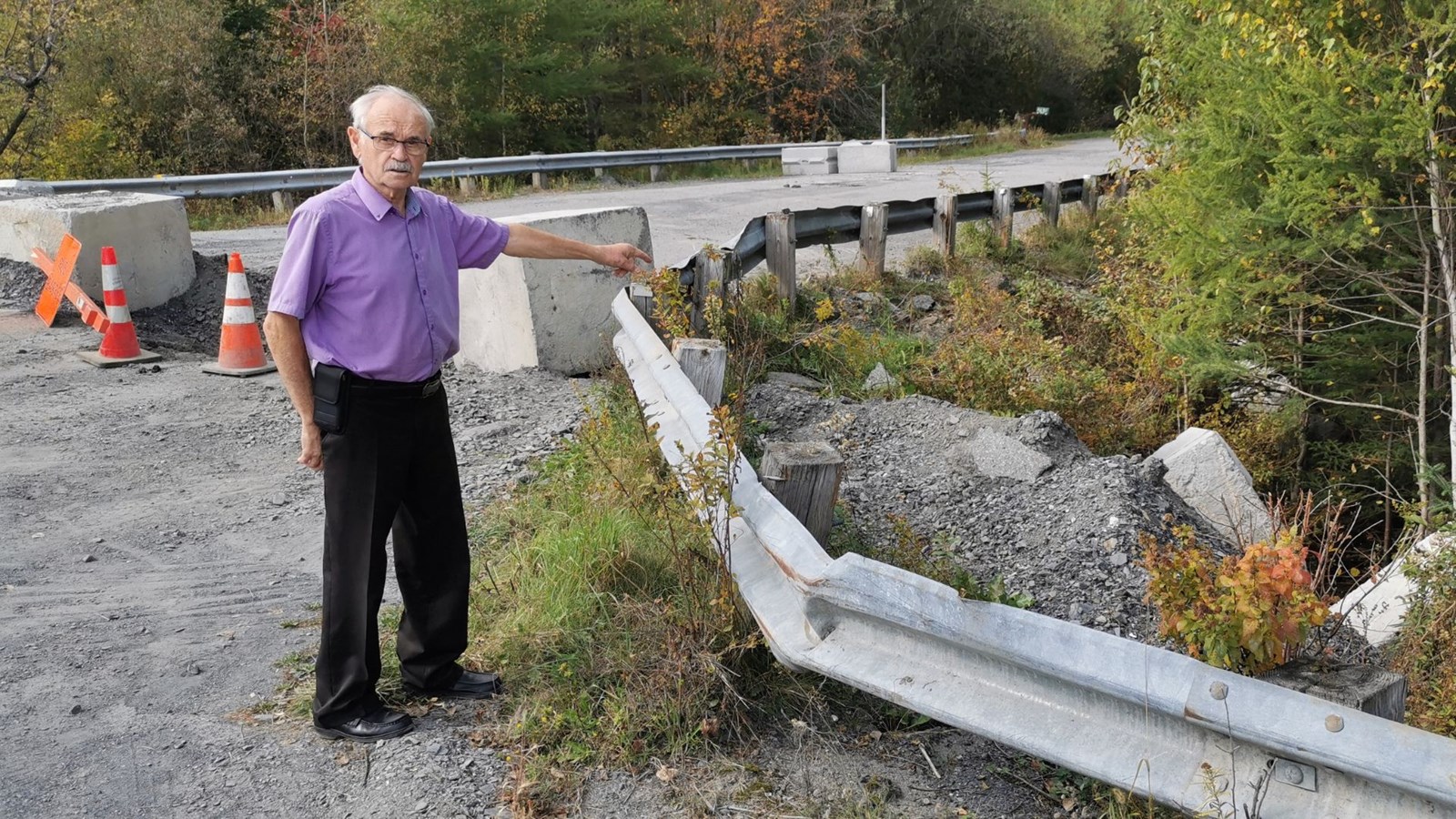 Le maire Jean-Roch Veilleux montrant les blocs de ciment poussés dans le ravin. C'est la quatrième fois que la barricade est vandalisée au cours des derniers mois.