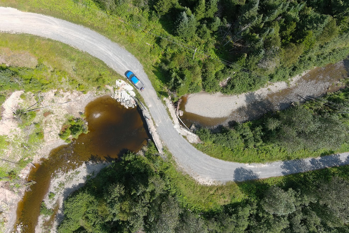 Vue aérienne d’un ponceau : sont visibles une problématique d’érosion des berges en amont (à gauche, avant l’ouvrage) et de sédimentation en sortie de ponceau (à droite)