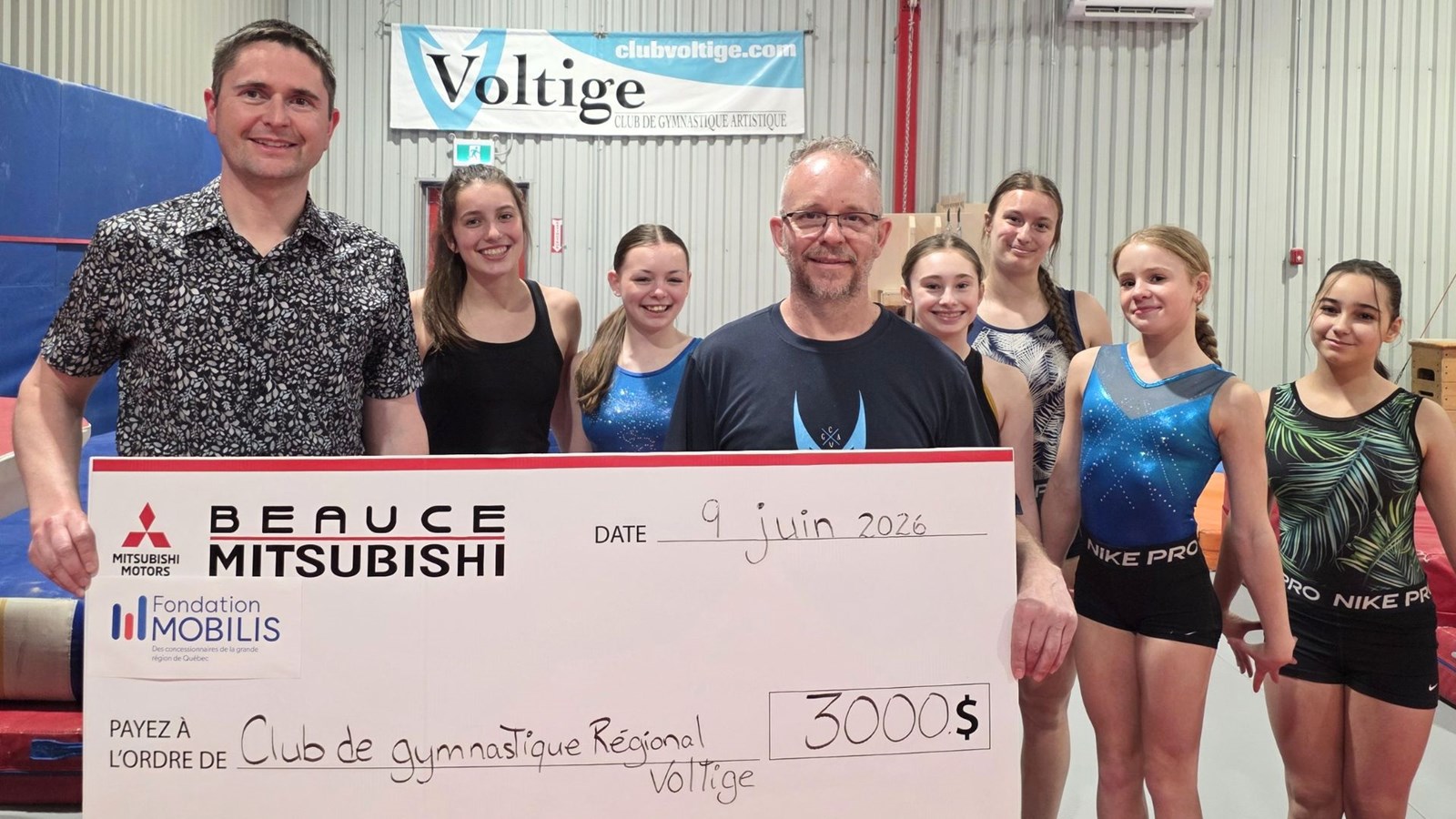 Sur la photo: Richard Fournier, directeur général du Club Voltige, accompagné de gymnastes du club, et de David Lessard, directeur général de Beauce Mitsubishi.
